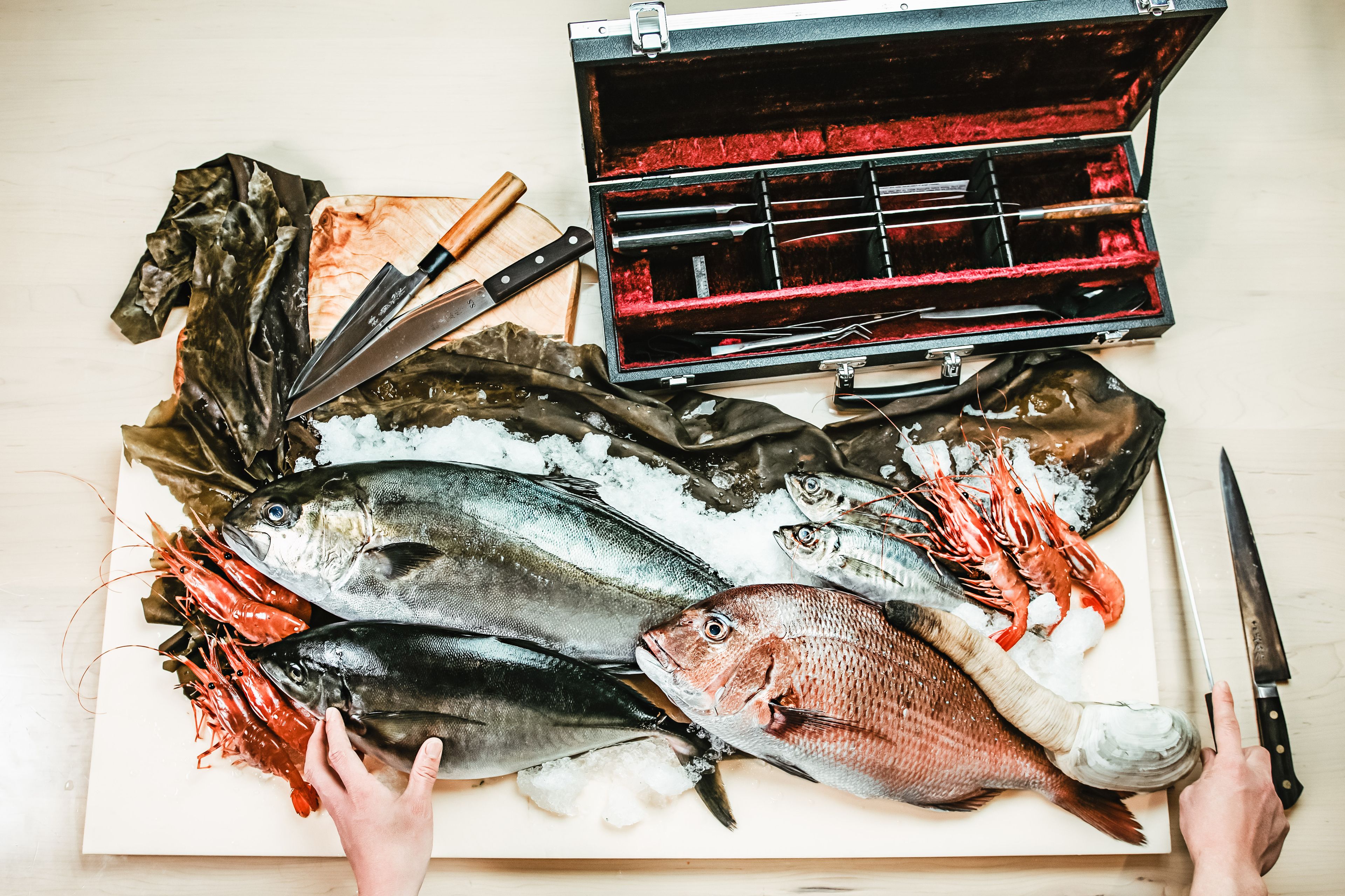 Variedad de mariscos frescos sobre una tabla de cortar, un cuchillo y un bloque para cuchillos.