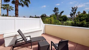 Relax on the balcony with a view of the lush green landscape and golf course beyond.
