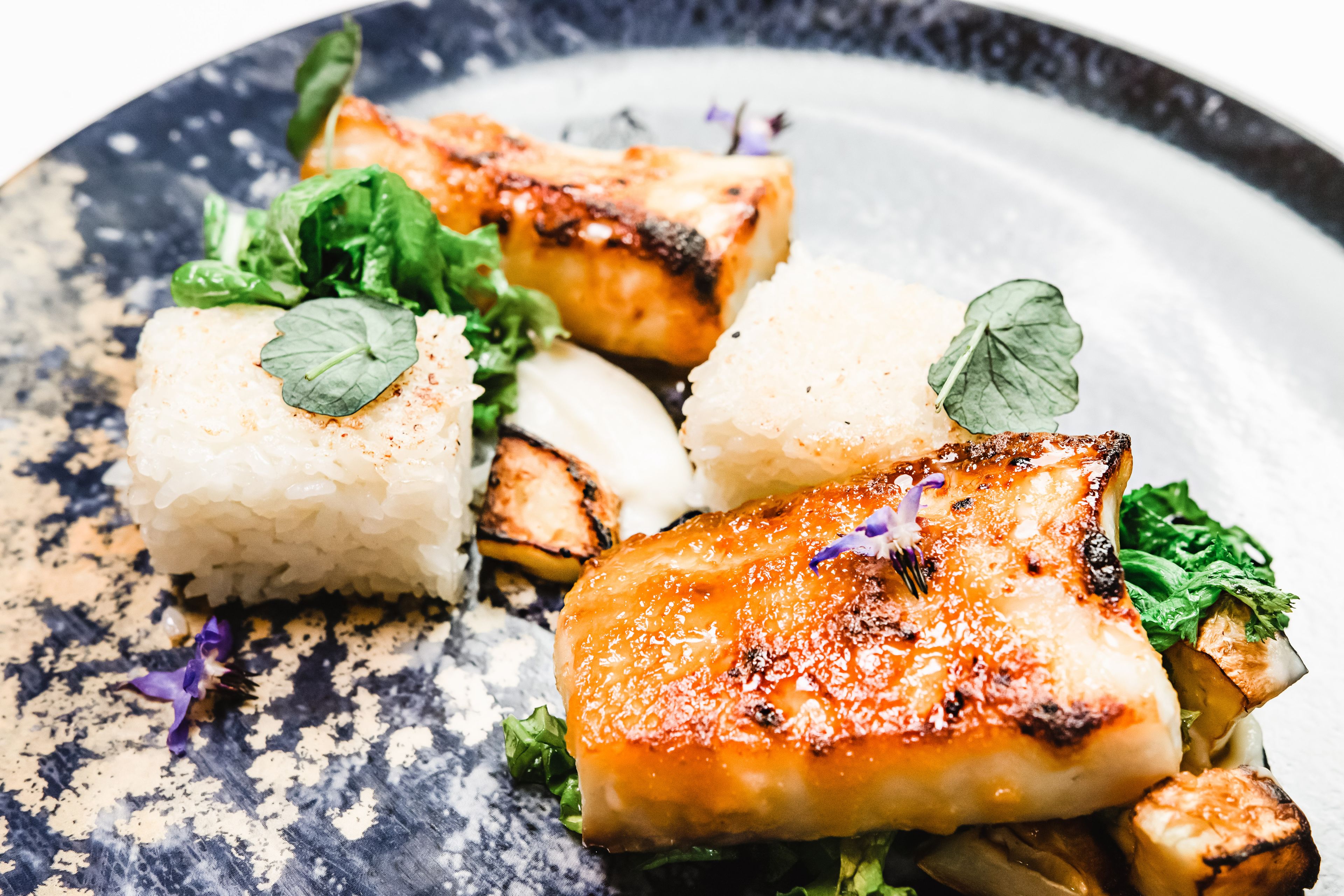 A plate of food with grilled fish, rice, and vegetables.
