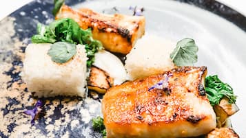 A plate of food with grilled fish, rice, and vegetables.
