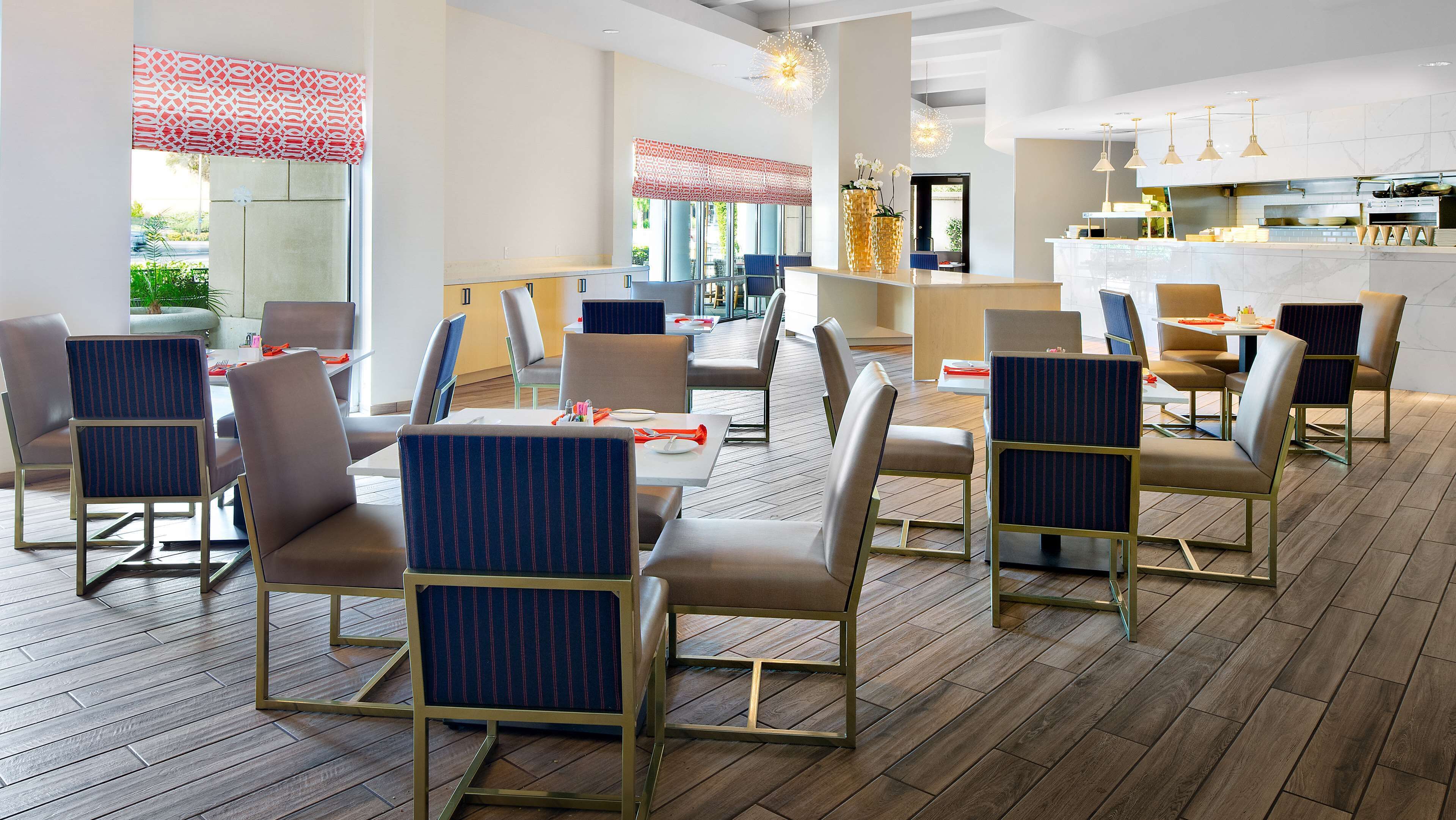 Un comedor moderno con suelo de madera, sillas de estructura metálica y una mesa central.