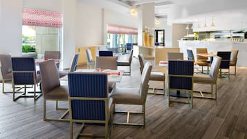 Un comedor moderno con suelo de madera, sillas de estructura metálica y una mesa central.