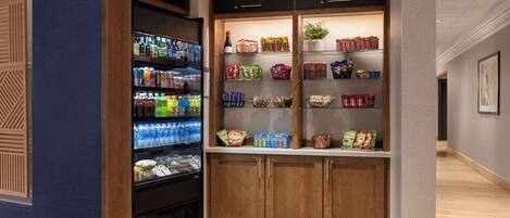 A hotel pantry with shelves stocked with snacks, beverages, and condiments.