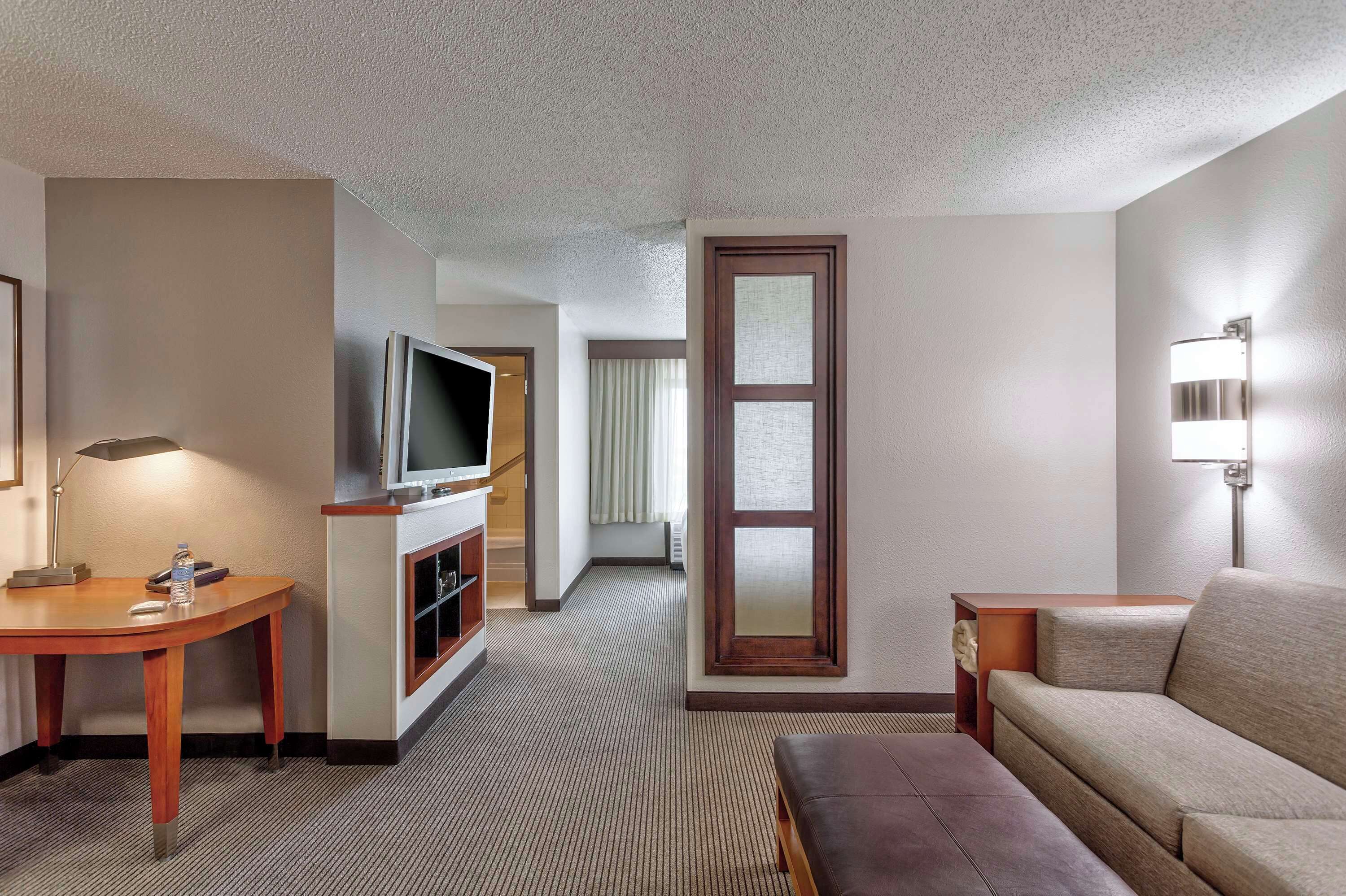 Une chambre d’hôtel équipée d’une télévision, d’un bureau, d’un canapé et d’une lampe.