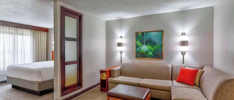 A hotel room with a bed, a sofa, a coffee table, and two wall-mounted lamps.