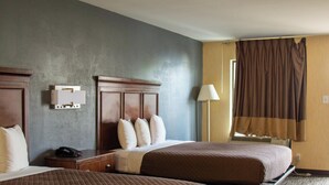 A hotel room with two beds, a bedside table with a phone, a lamp, and a window with curtains. - Brentwood Inn & Suites (Glen Allen)