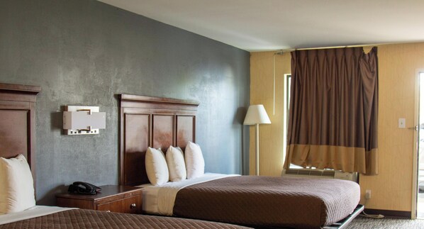 A hotel room with two beds, a bedside telephone, a lamp, and a window with curtains. - Brentwood Inn & Suites (Glen Allen)