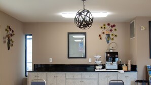 A kitchen with a black countertop, a coffee machine, and a decorative vase with flowers. - Brentwood Inn & Suites (Glen Allen)