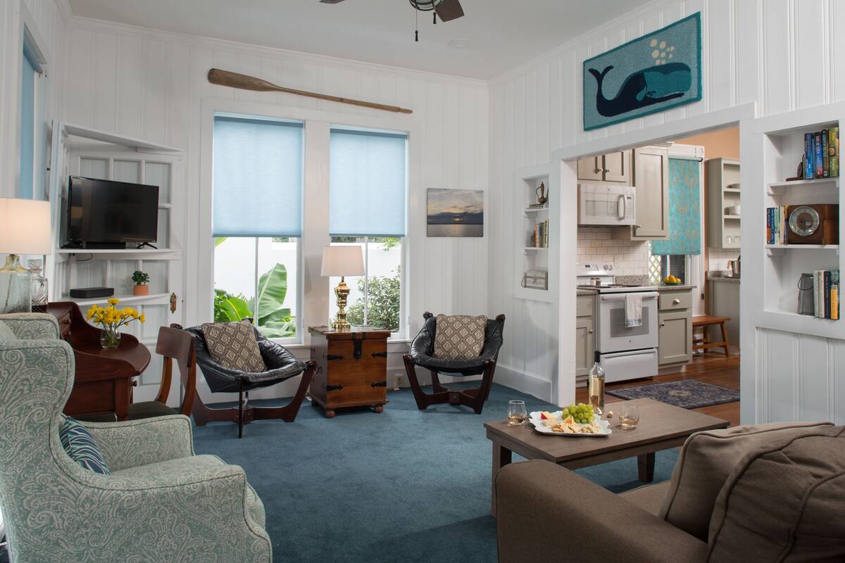 A living room with a television, two armchairs, a coffee table, and a dining area with a table set for two.