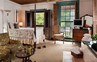 A bedroom with a four-poster bed, a chair, a dresser, and a television.