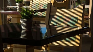 A dining area with a glass table, wooden chairs, and potted plants.