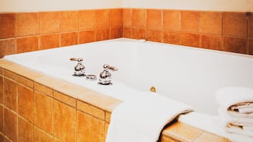 A bathroom with a bathtub, a towel rack with towels, and a window above the tub.