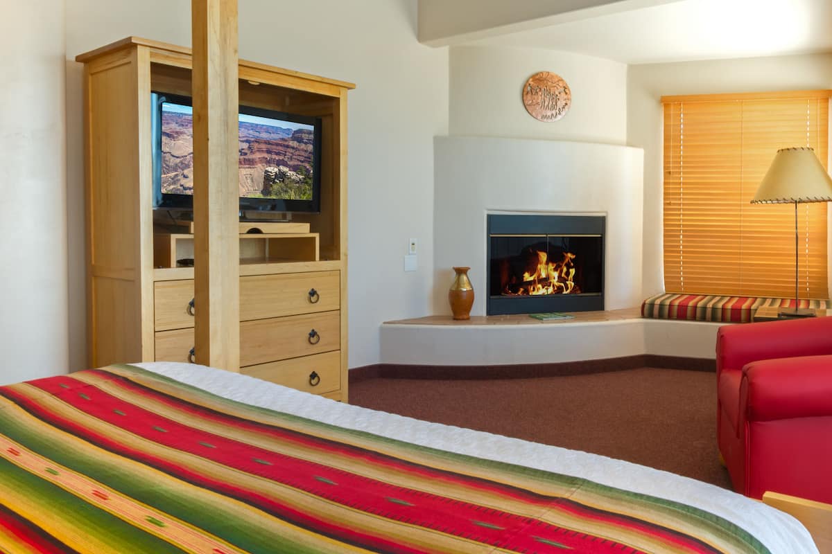 A hotel room with a large bed, a television, a fireplace, and a red sofa.