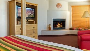 A hotel room with a large bed, a television, a fireplace, and a red sofa.