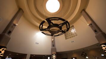 Un interior moderno con diseño de techo circular, un elemento de iluminación central y una columna destacada con un símbolo de estrella.