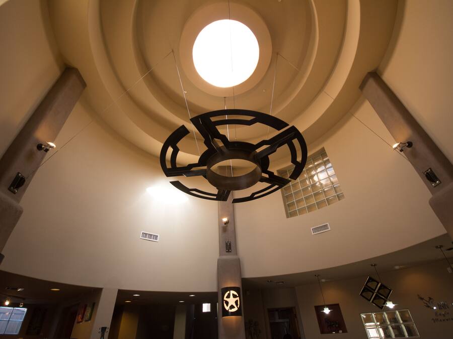 Un interior moderno con diseño de techo circular, un elemento de iluminación central y una columna destacada con un símbolo de estrella.