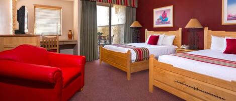 A hotel room with two wooden beds, a red sofa, a desk, and a window with blinds.