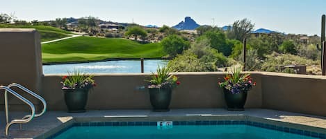 A swimming pool with a view of a golf course and a mountain in the background.