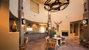 A lobby with stone flooring, wooden furniture, a fireplace, and modern lighting fixtures.