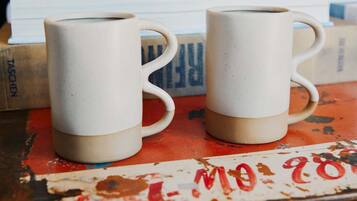 Two white ceramic mugs on a table with a red and white patterned surface.