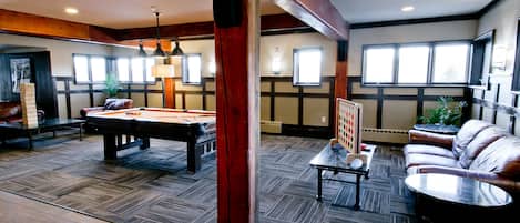 A spacious room with a pool table, leather sofa, and a billiards table.