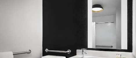A modern bathroom with a white sink, a large mirror, and a black accent wall.