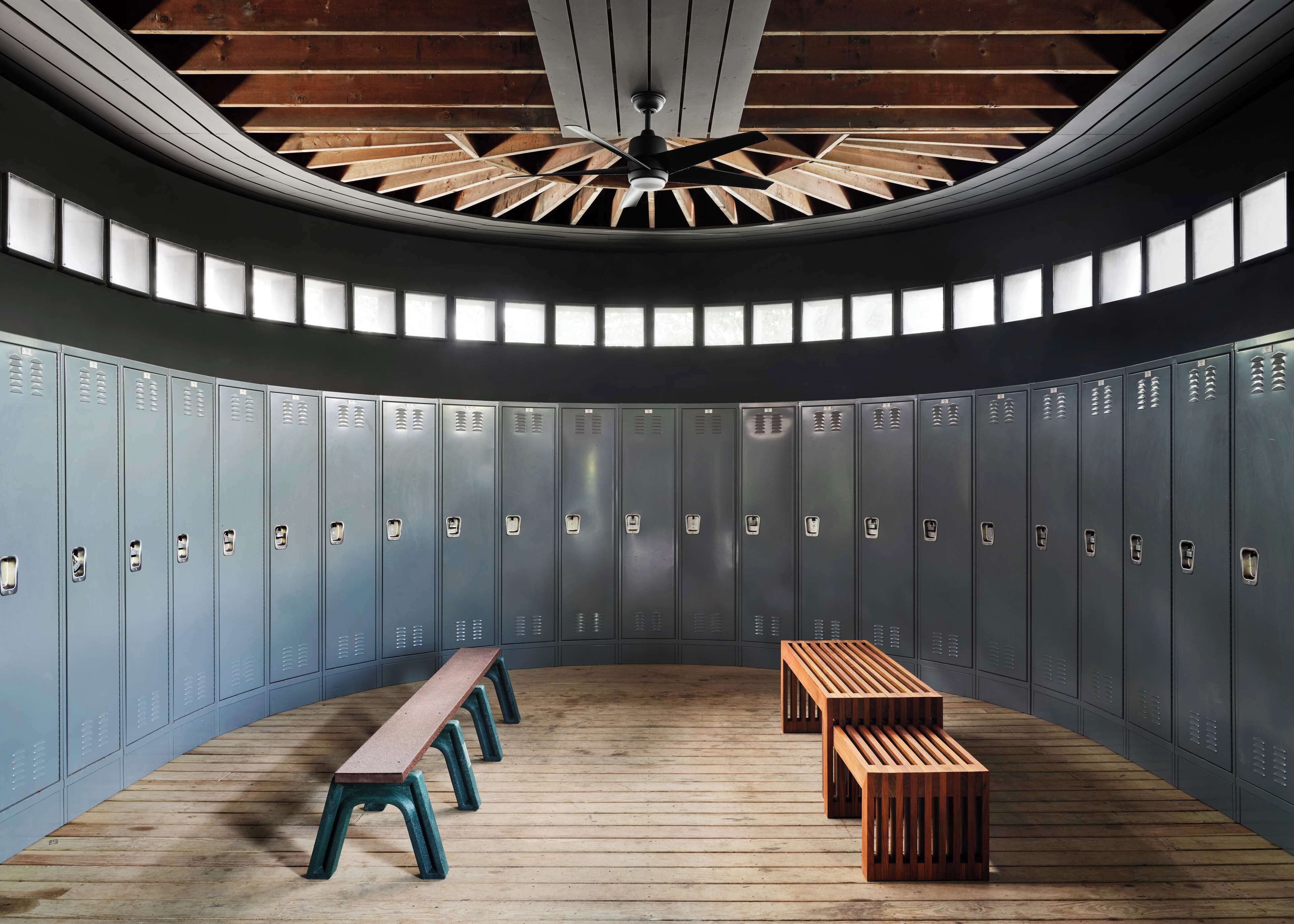 A circular room with lockers, benches, and a wooden ceiling.