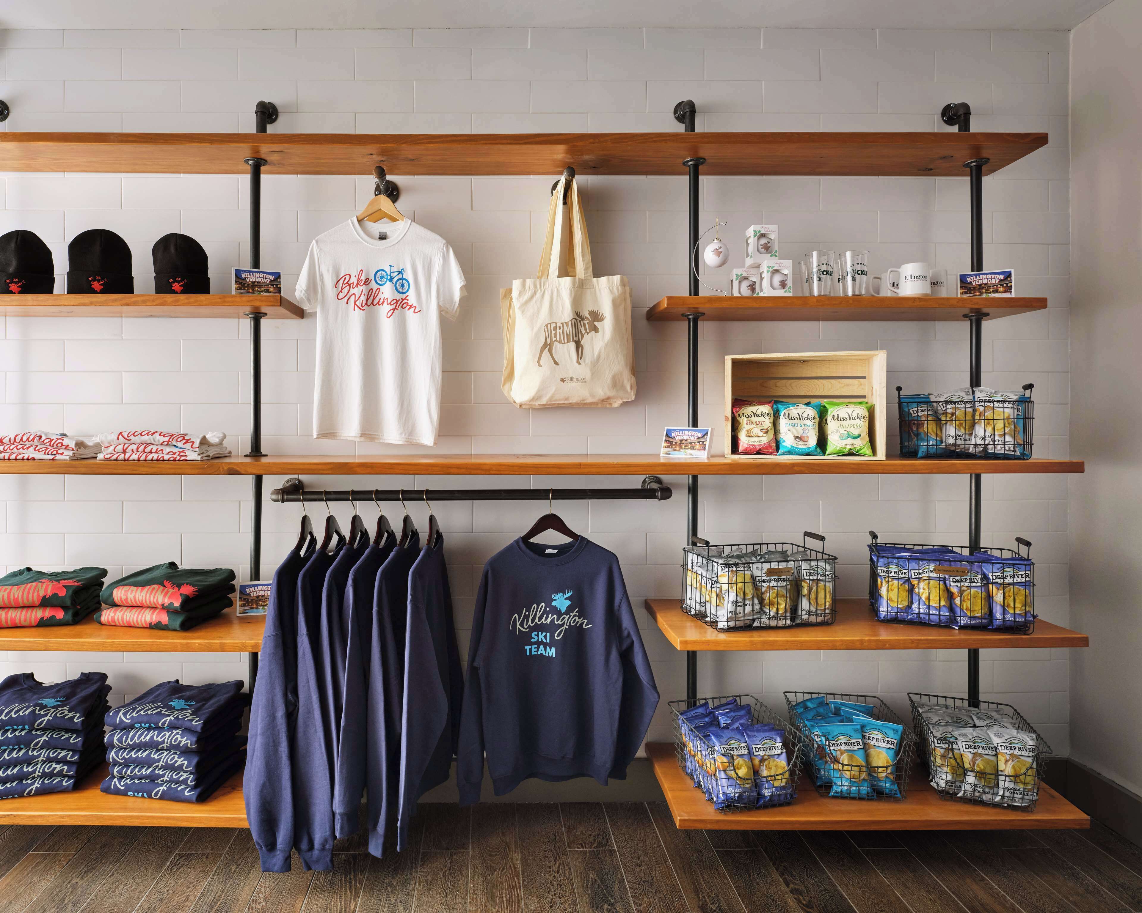 Un magasin de détail où des étagères présentent différents articles, notamment des t-shirts et des en-cas.