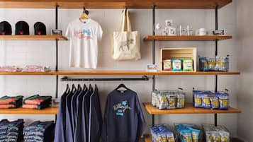 Loja de varejo com prateleiras exibindo produtos, incluindo camisetas e lanches.