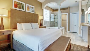 Ein Hotelzimmer mit einem großen Bett, einer Sitzbank, einem Badezimmer mit Dusche und einem Schminktisch.