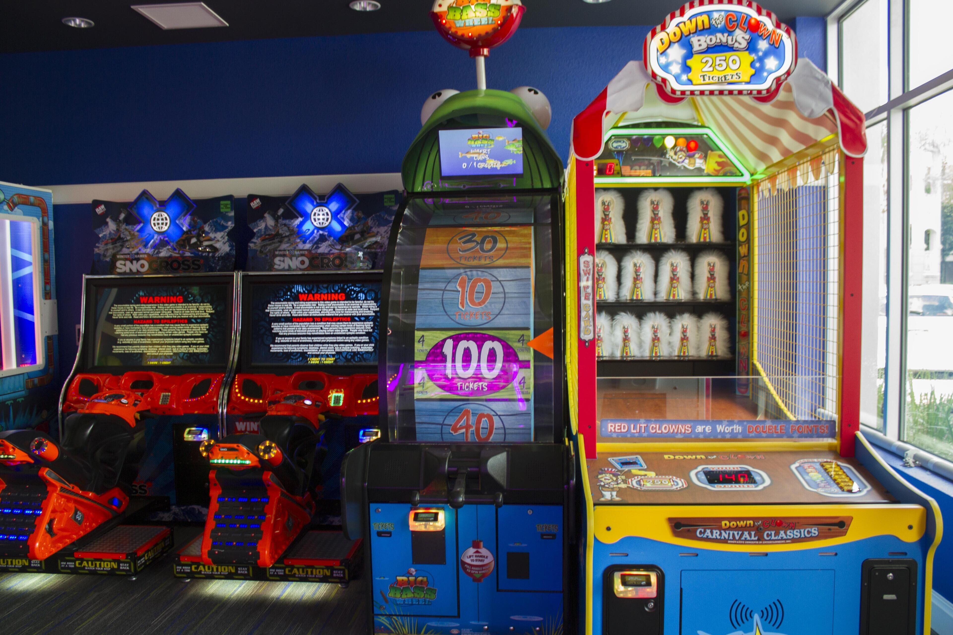 Une rangée de bornes d’arcade proposant divers jeux et des guichets de distribution de tickets.