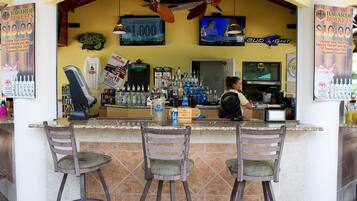 Eine Bar mit einer Theke, Hockern und einem Fernseher.