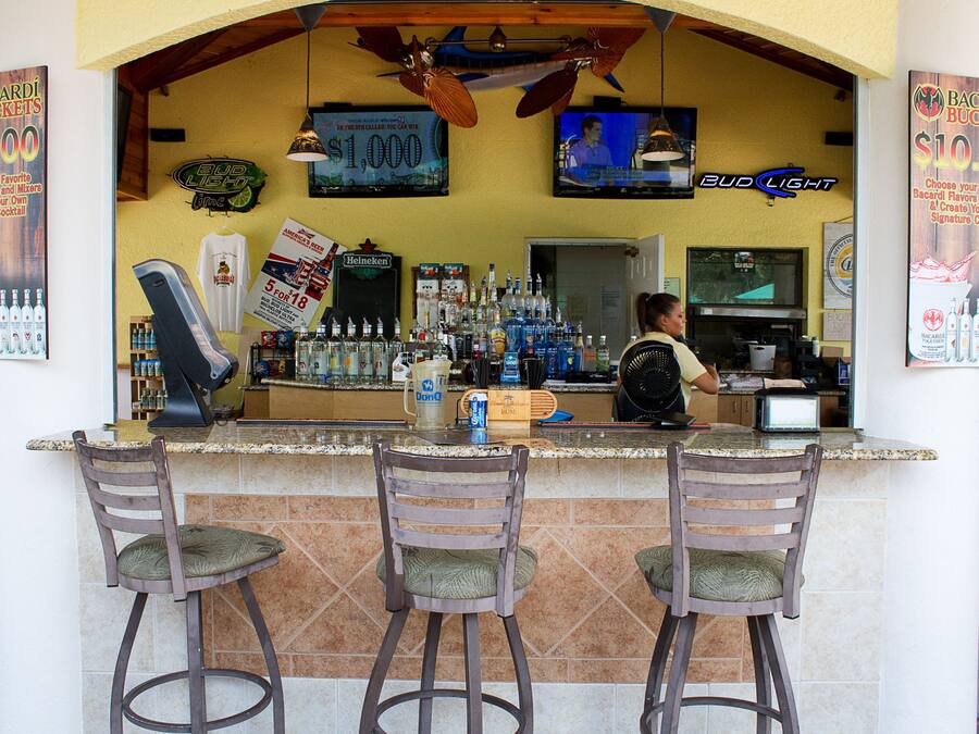 Eine Bar mit einer Theke, Hockern und einem Fernseher.