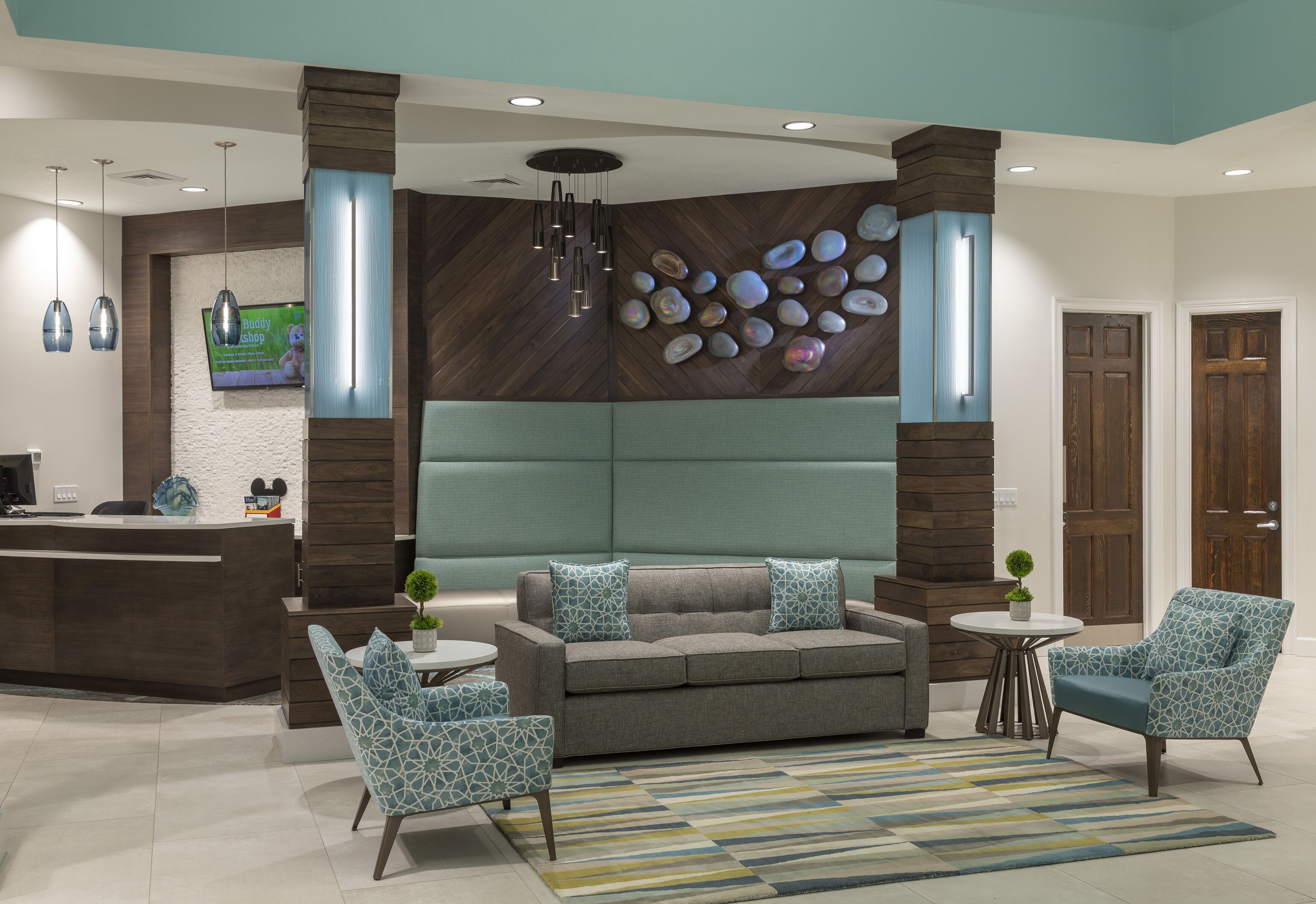 A modern lobby with a reception desk, seating area, and decorative wall with shells.