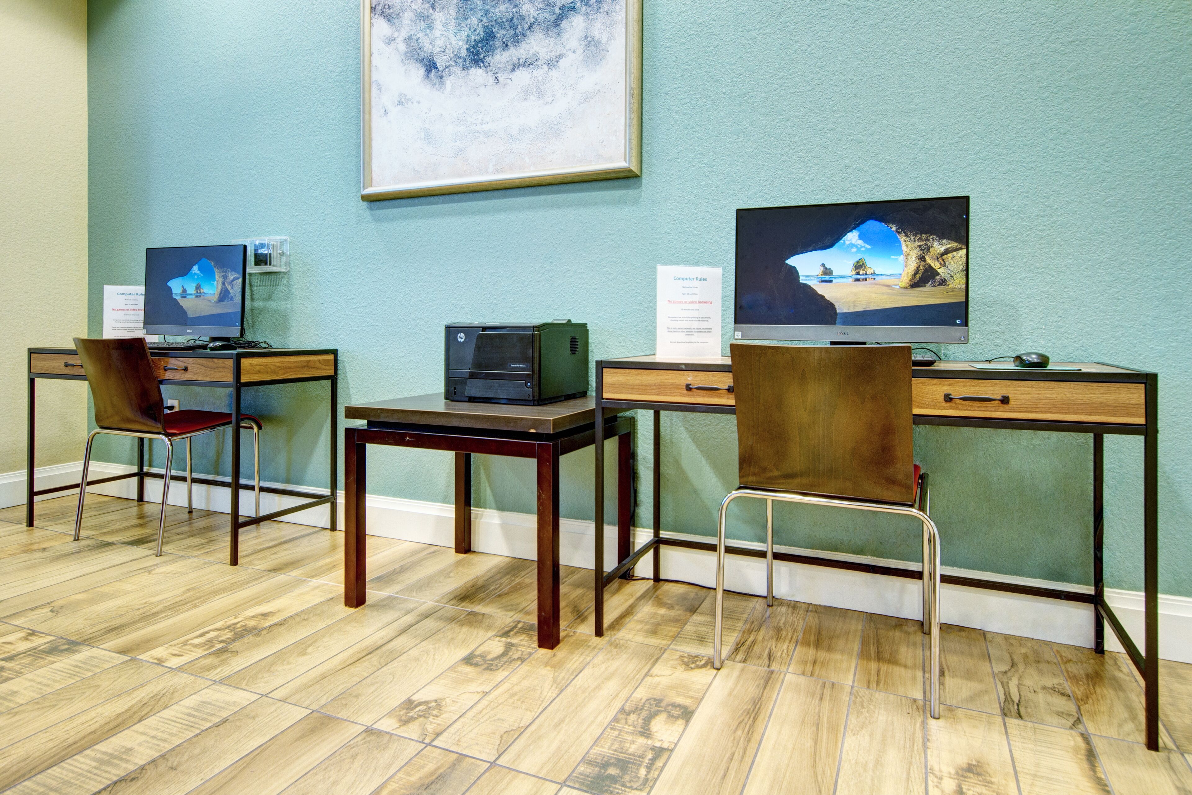 A computer lab with three desks, each with a computer and a chair.