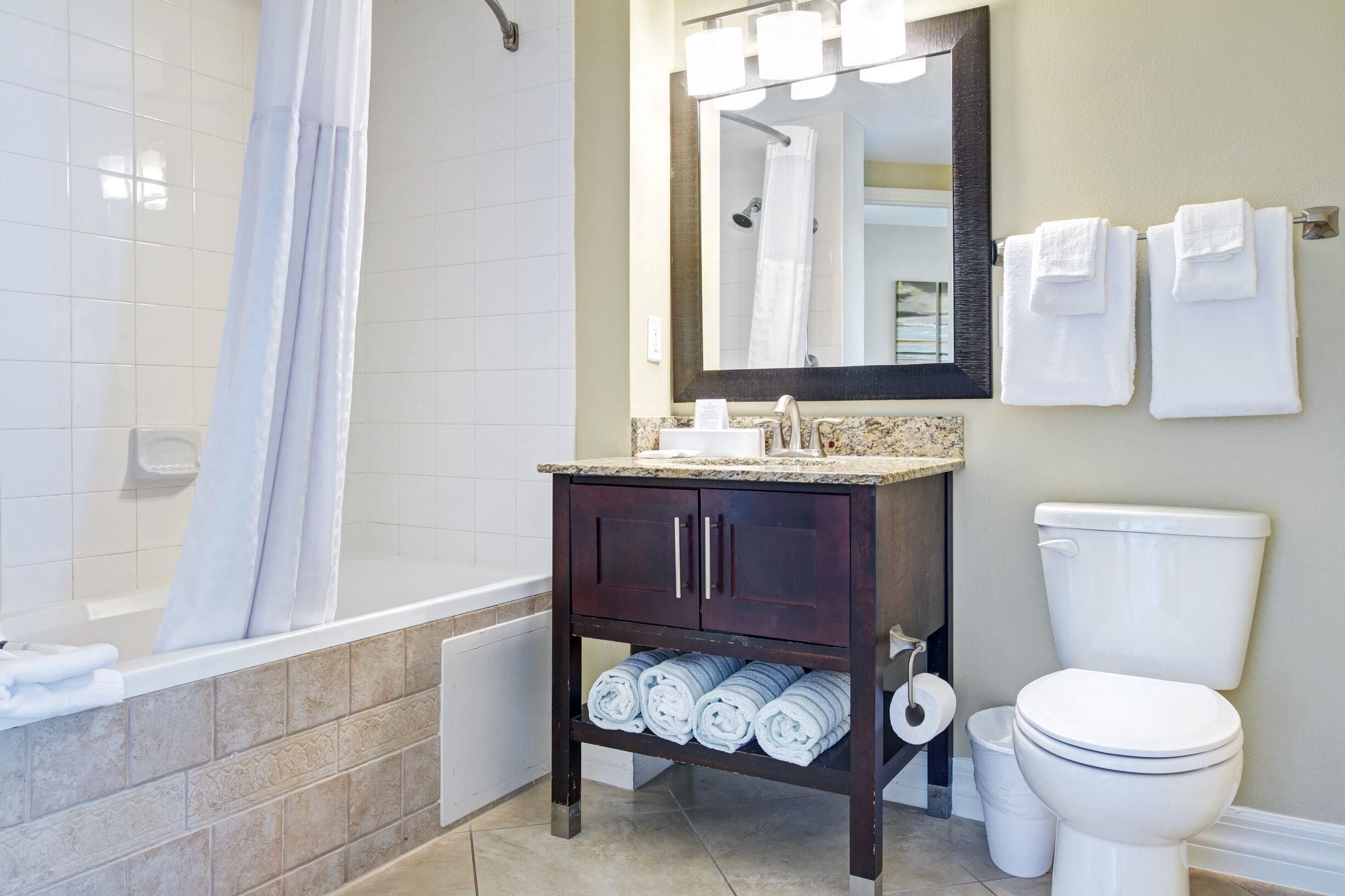 A bathroom with a bathtub, a toilet, a sink, a mirror, and towels.