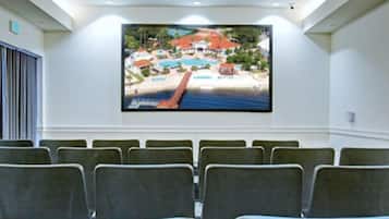Une salle de conférence dotée d’un grand écran affichant une image d’un complexe hôtelier, de rangées de chaises et d’un plafond équipé d’un éclairage encastré.