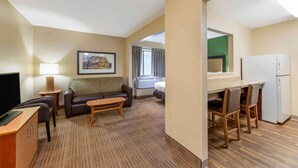 A hotel room with a sofa, a small table, a TV, a desk with chairs, a refrigerator, and a window with curtains. - Extended Stay America Suites Cleveland Westlake (Westlake)