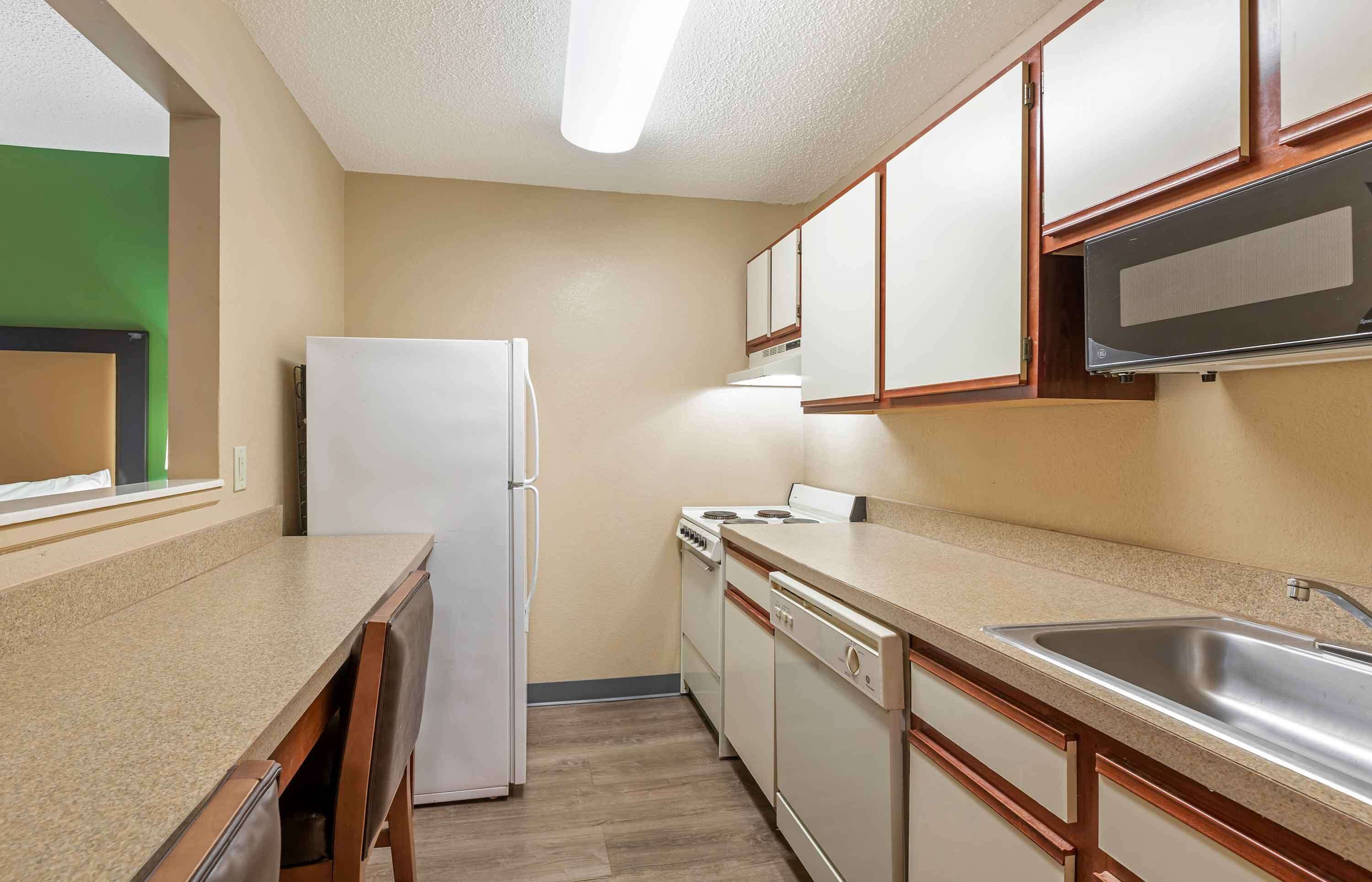 A compact kitchen with a refrigerator, stove, microwave, and sink.