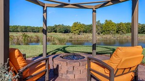A gazebo with a fire pit and two orange chairs facing a pond. - Hilton Vacation Club St. Augustine (St. Augustine)