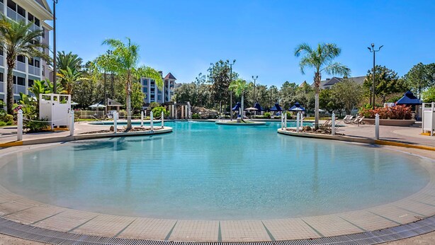 A large, circular swimming pool with clear blue water, surrounded by palm trees and lounge chairs. - Hilton Vacation Club St. Augustine (St. Augustine)