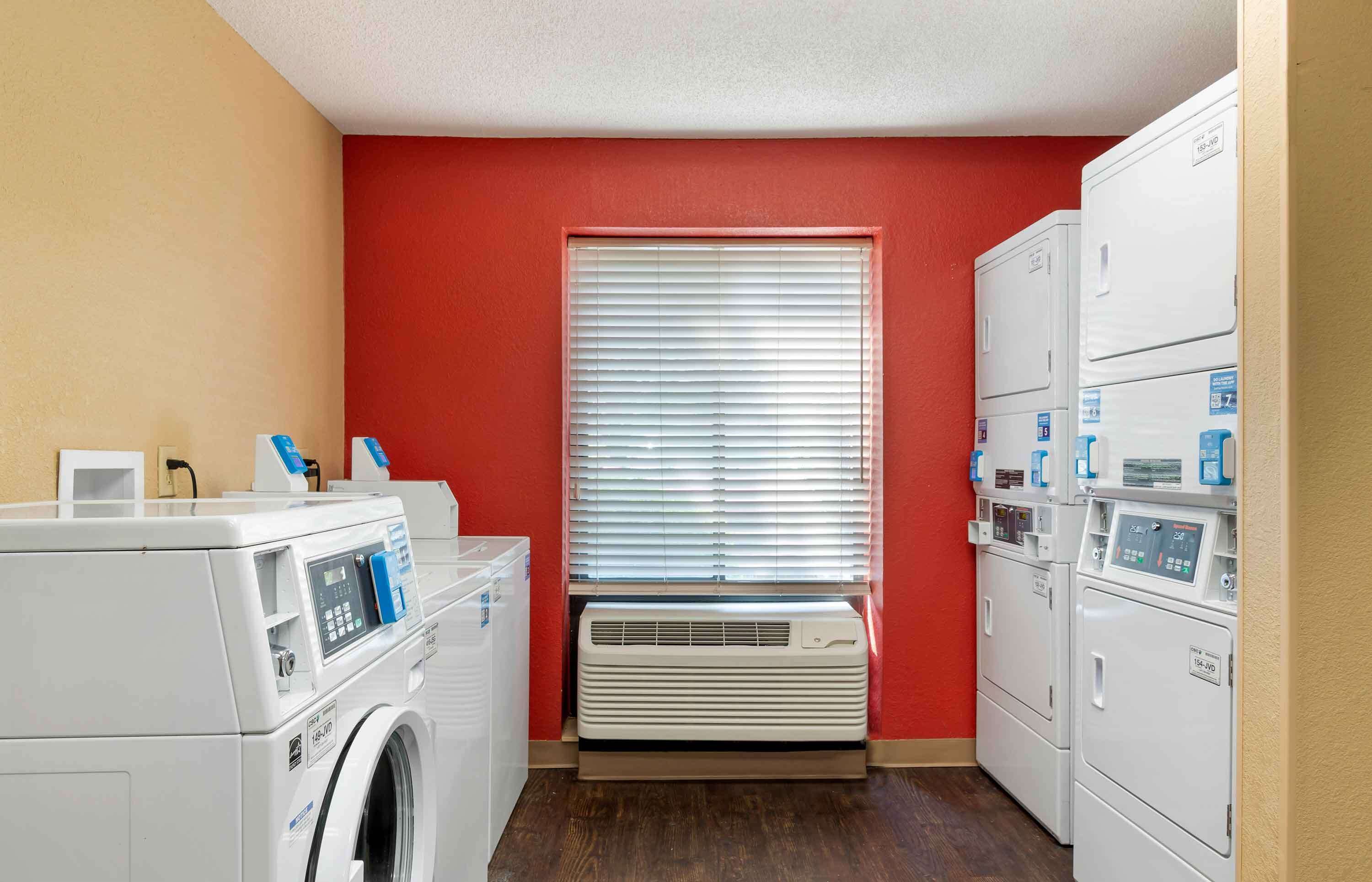 Une buanderie équipée d’un lave-linge, d’un sèche-linge et de plusieurs sèche-linge superposés.
