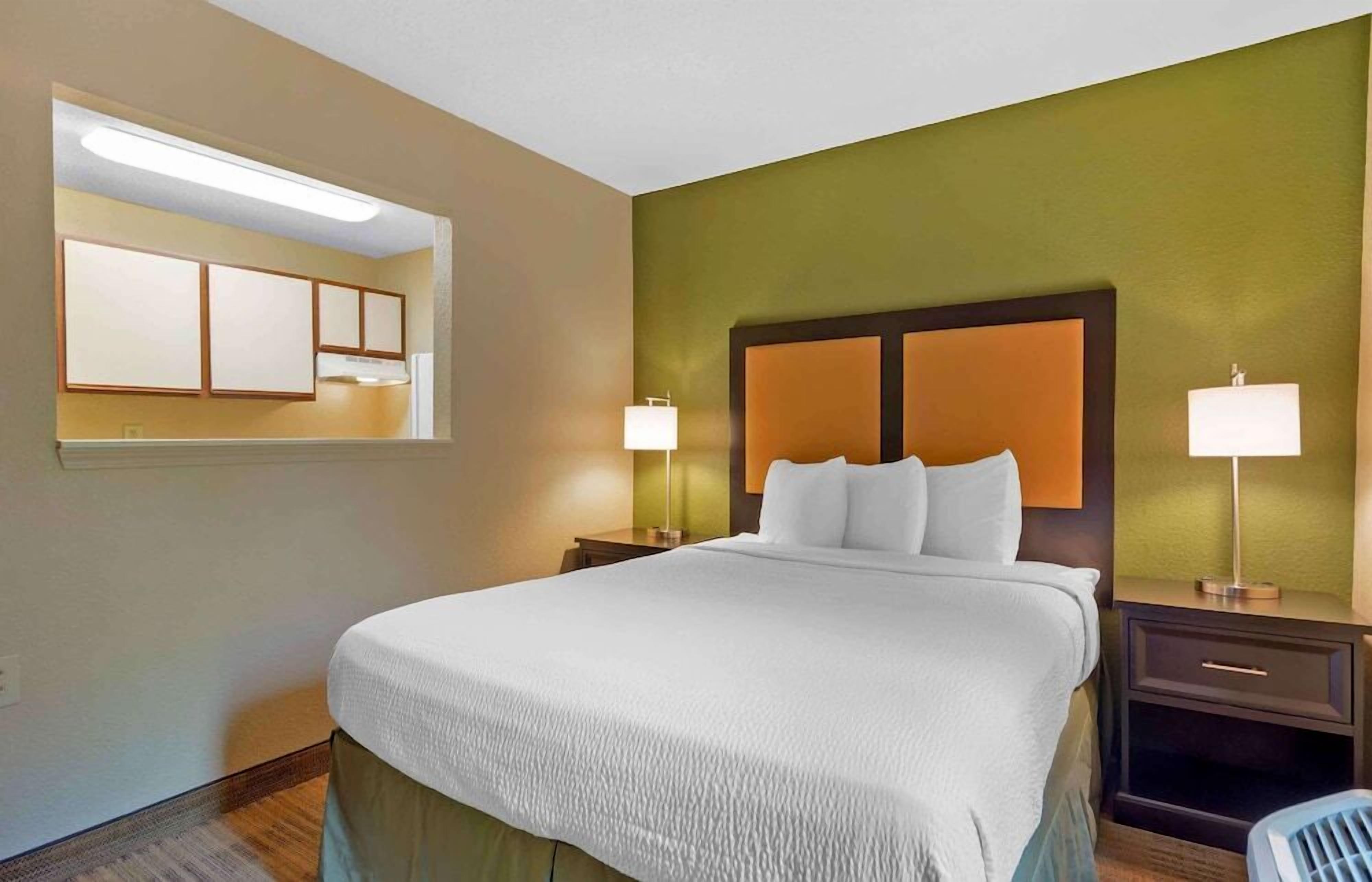 Une chambre d’hôtel avec un lit, des tables de chevet, un miroir et une fenêtre.