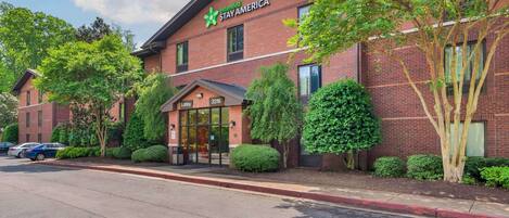 A brick building with a sign for Extended Stay America, featuring a lobby entrance and a parking area.