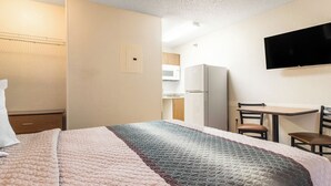 A hotel room with a bed, a desk, a chair, a television, and a kitchenette. - HomeTowne Studios by Red Roof Houston - West Oaks/ Energy Corridor (Houston)