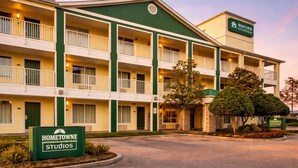 Un hotel de varios pisos con fachada verde y color crema, balcones y un letrero que dice Hometown Studios.
