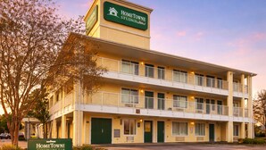 Un motel de varios pisos con un letrero que dice 'HOMETOWNE STUDIOS'.