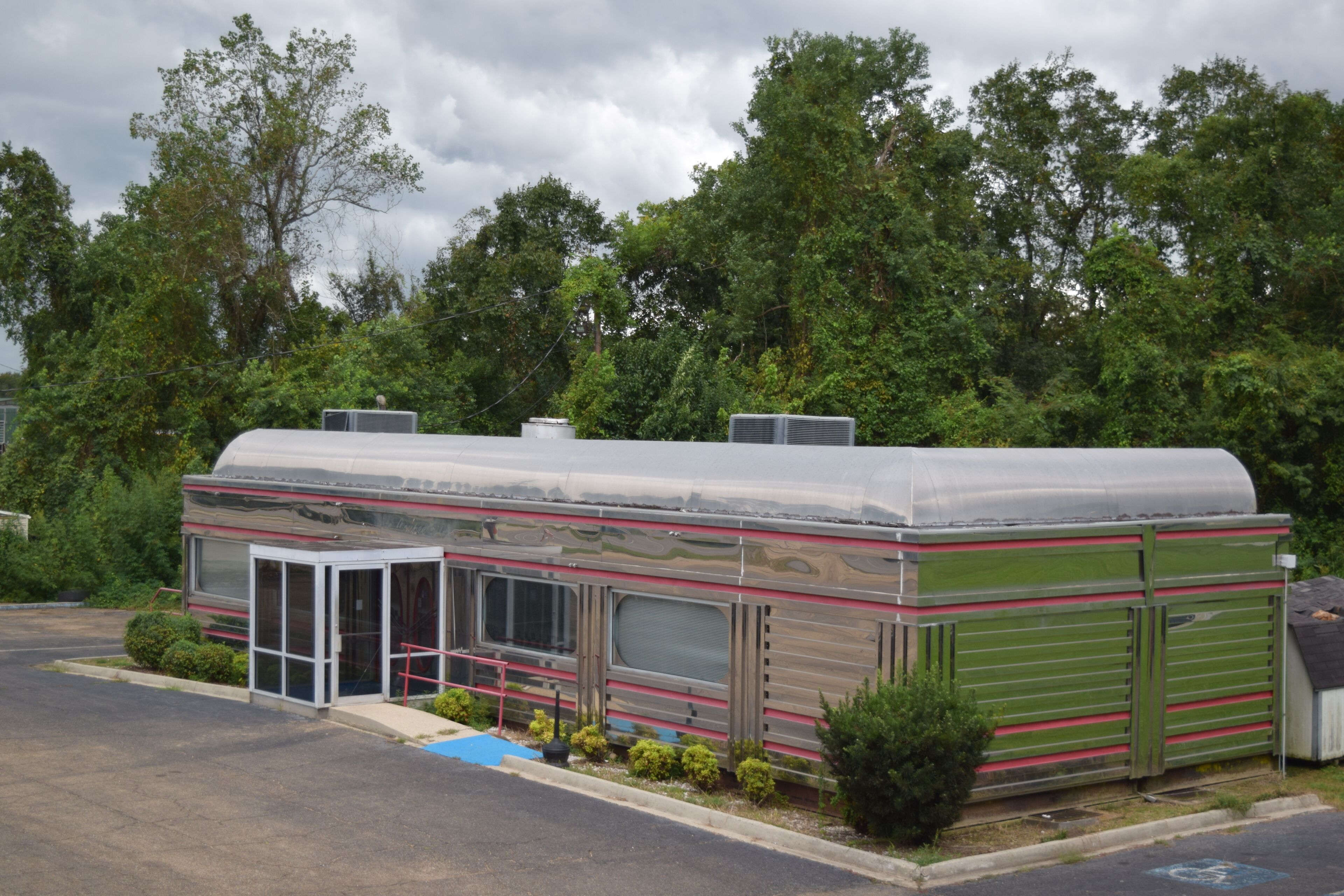 Une maison mobile dotée d’un porche couvert, d’une petite dépendance attenante et d’un espace de stationnement dallé.