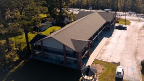 An aerial view of a building with a flat roof, surrounded by trees and a parking lot. - Value Inn Livonia (Livonia)