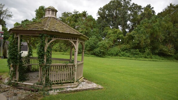 A gazebo with a wooden structure and a roof, surrounded by a grassy area and trees. - Value Inn Livonia (Livonia)